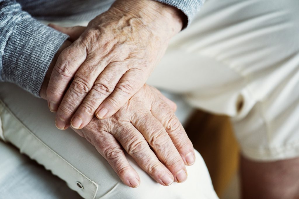 Visibly aged hands on lap.