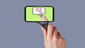Hand holding a smart-phone shaped magnifying glass.